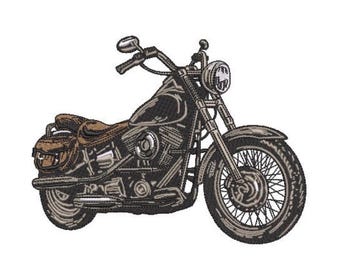 May include: An embroidered patch design of a cruiser motorcycle in shades of black, grey, and brown. The motorcycle features a prominent round headlight, spoked wheels, a brown leather-coloured seat, and matching brown saddlebags on the rear.