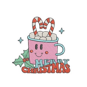 May include: An embroidered design of a pink mug with a smiling face, filled with white marshmallows and two red and white striped candy canes. The mug features a light blue handle and rim, green holly leaves with red berries, and the text MERRY CHRISTMAS.