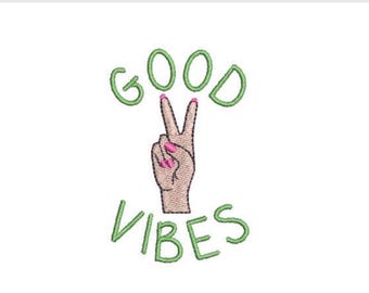 May include: An embroidery design featuring the text GOOD VIBES in light green thread. Centered between the words is a hand making a peace sign gesture with pink fingernails, rendered in tan and pink thread against a plain white background.