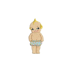 May include: A vintage-style embroidered patch of a blonde baby doll wearing a blue and white patterned diaper. The doll has a sweet expression and is standing with its hands on its hips.