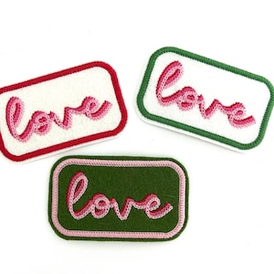 Puede incluir: Tres parches bordados para planchar con la palabra "love" en letras cursivas rosas. Los parches están sobre un fondo blanco. Un parche tiene un borde rojo, otro un borde verde y otro un borde verde con un contorno rosa.