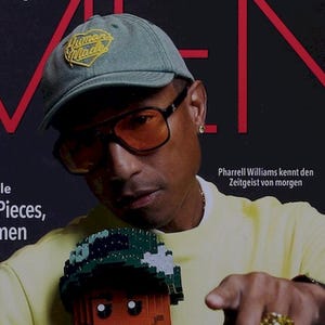 Puede incluir: Portada de revista con Pharrell Williams con gorra verde y gafas naranjas, sosteniendo una figura de Lego. La portada presenta el texto "InStyle MEN" y texto en alemán. La portada de la revista también tiene el texto "AB IN DIE ZUKUNFT!" y "FUTURISTIC SNEAKERS".