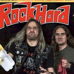May include: Rock Hard magazine cover featuring two men, one holding fries. The magazine title is in large red letters. Text includes "EXKLUSIV!" and band names. The cover has a black background with various text elements.