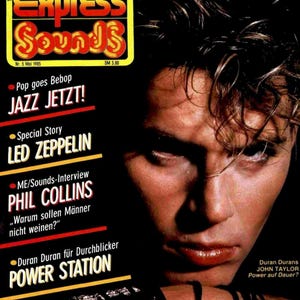 Puede incluir: Una portada de revista vintage Musik Express Sounds de mayo de 1985 con un retrato de John Taylor. La portada incluye titulares sobre Led Zeppelin, Phil Collins y Power Station, con un fondo oscuro y una marca en amarillo y rojo.