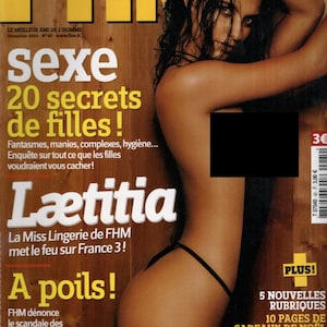 Puede incluir: La edición de diciembre de 2004 de la revista FHM presenta una portada con una persona en lencería negra sobre un fondo de madera. El texto incluye 'sexe 20 secrets de filles', 'Laetitia', 'A poils' y otros titulares en amarillo y blanco.