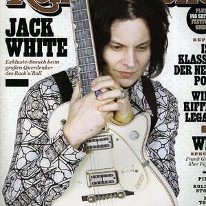 Puede incluir: Portada de la revista Rolling Stone con Jack White sosteniendo una guitarra Gretsch blanca. El texto de la portada incluye "JACK WHITE" y texto en alemán. El fondo es una mezcla de blanco y negro. Revista musical.