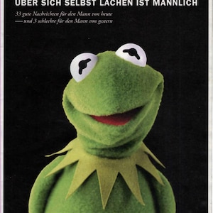 May include: A green Kermit the Frog puppet with white eyes and a red mouth. The image includes text in German: "ZEIT MANN" and "ÜBER SICH SELBST LACHEN IST MÄNNLICH".