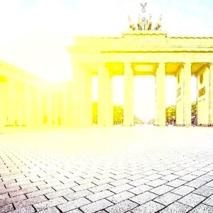 Puede incluir: Vista soleada de la Puerta de Brandeburgo en Berl&iacute;n. El monumento neocl&aacute;sico presenta columnas y arcos, con un cielo despejado arriba. El primer plano muestra un pavimento de adoquines que conduce al emblem&aacute;tico monumento.
