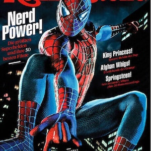 Può includere: Una copertina della rivista Rolling Stone con Spider-Man in un costume rosso e blu accovacciato contro uno skyline urbano scuro. Il testo recita Nerd Power!, King Princess!, Afghan Whigs!, Springsteen!, Ezra Furman, Judith Holofernes, Conor Oberst, PJ Harvey, Amanda Shires.