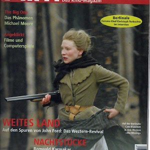 Puede incluir: Una portada de revista titulada epd Film 2/04 que muestra a una persona con chaqueta verde y bufanda oscura sosteniendo un arma larga. El texto incluye The Big One, Michael Moore, Berlinale, Weites Land y Nachtstücke. El fondo muestra un bosque borroso.