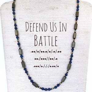 Handcrafted beaded necklace featuring Morse code pattern spelling out 'defend us in battle'. Muted colors of green and and blue spell out the St Michael prayer quote.