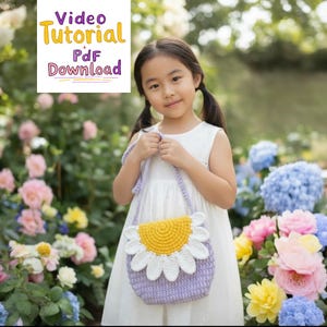 May include: A crocheted daisy purse with a yellow center and white petals, held by a person in a white dress. The purse is lavender with a matching strap. Text in the upper left corner reads "Video Tutorial PDF Download". The background features colorful flowers.