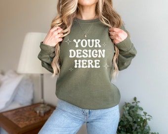 Puede incluir: Una mujer lleva una sudadera verde con el texto "YOUR DESIGN HERE" en blanco. La sudadera tiene un corte holgado y mangas largas.