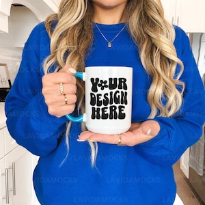 May include: A white ceramic mug with a turquoise handle. The mug has black text that reads "YOUR DESIGN HERE" in a retro font.