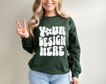 May include: A dark green sweatshirt with the text "YOUR DESIGN HERE" in white, retro-style lettering. The sweatshirt is made of a soft, comfortable fabric and has a relaxed fit.