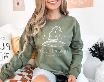 May include: A green sweatshirt with a white witch hat graphic and the text "Your Design" on the front. The sweatshirt is being worn by a person with long blonde hair.