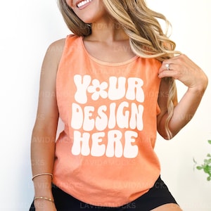 May include: A peach-colored sleeveless tank top with the text "YOUR DESIGN HERE" in white, stylized lettering.
