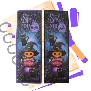May include: Two purple and black Halloween themed bookmarks with a black cat, a witch with a cauldron, and the text "I put a spell on you".