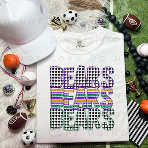 Puede incluir: Camiseta blanca con la palabra "BEARS" en un diseño apilado. Las letras son a cuadros blancos y negros con rayas moradas, verdes y doradas. Una gorra de camionero blanca, pelotas deportivas y trofeos están dispuestos alrededor de la camisa.