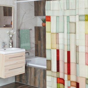 The shower curtain shown has a geometric pattern made up of squares and rectangles in varying sizes. These shapes are filled in with watercolor and are arranged in a random pattern. Colors include shades of pink, peach, yellow, red, green, and brown.