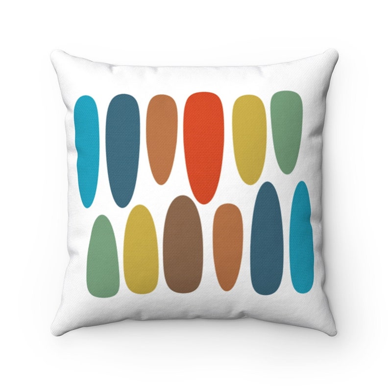 White throw pillow with a mid-century modern design featuring rows of colorful vertical ovals in blue, orange, green & yellow