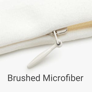 Close-up of a white brushed microfiber pillow cover with a hidden zipper, showing soft fabric texture and clean stitching.