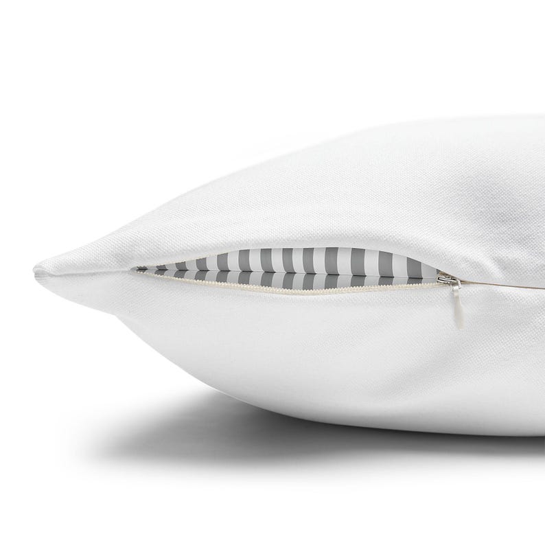 Close-up of a white pillow’s side concealed zipper, showing a gray & white striped inner insert against a white background.