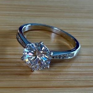 Moissanite ring. A delicious 3ct certified Moissanite solitaire with tapered shoulders and pavé-set white zircons in sterling and 18k gold!