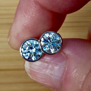 May include: A pair of silver stud earrings with clear round cubic zirconia stones.