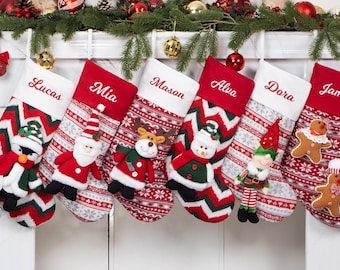May include: Six personalized Christmas stockings with red and white striped patterns and various plush characters, including a penguin, Santa Claus, reindeer, snowman, elf, and gingerbread man. The stockings are hung on a white fireplace mantel with greenery and ornaments.
