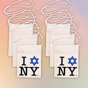 May include: Off-white canvas crossbody bags with a zipper closure and a white cord strap. Each bag features the text "I NY" with a blue Star of David symbol. The bags are displayed on a gradient background.