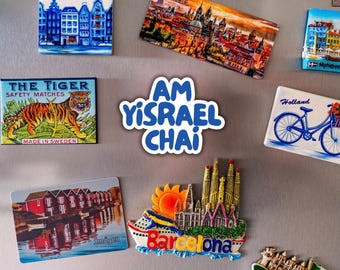May include: A collection of various rectangular and shaped souvenir magnets featuring colorful illustrations of cityscapes, landmarks, and a tiger, along with a central white die-cut magnet displaying the blue text AM YISRAEL CHAI.