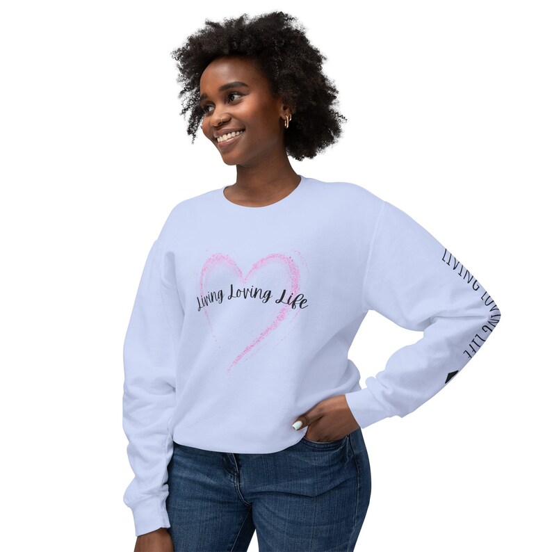 May include: A light blue sweatshirt with a pink heart and the text "Living Loving Life" on the front. The text "Living Loving Life" is repeated on the sleeves.