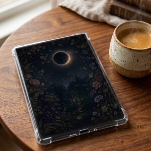 Op de afbeelding: Een doorzichtige beschermhoes voor een tablet met een donkere, gedetailleerde illustratie van een zonsverduistering boven een weelderige tuin met bloeiende bloemen, groen en een stenen boogpad onder een sterrenhemel.