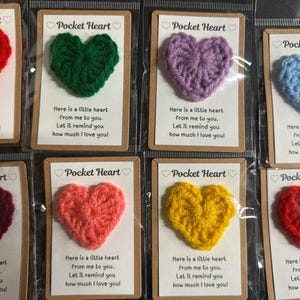 Peut inclure: Huit petites décorations en forme de cœur en crochet sur des cartes avec le texte "Pocket Heart" et le message "Voici un petit cœur de moi pour toi. Laisse-le te rappeler combien je t'aime !"