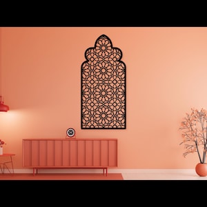 Peut inclure: Une décoration murale en métal noir avec un motif géométrique complexe, ressemblant à une fenêtre ou une arche. La décoration est montée sur un mur de couleur pêche.
