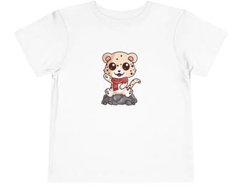 May include: White t-shirt with a cartoon illustration of a cheetah wearing a red scarf and sitting on a rock.
