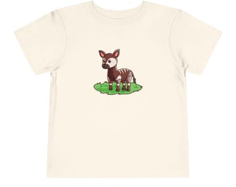 May include: A white t-shirt with a cartoon image of an okapi standing on a patch of green grass.