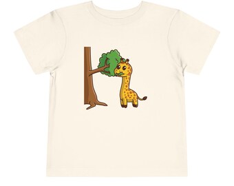 May include: A white t-shirt with a cartoon illustration of a giraffe eating leaves from a tree. The giraffe is yellow with brown spots and has a long neck. The tree is brown with green leaves.