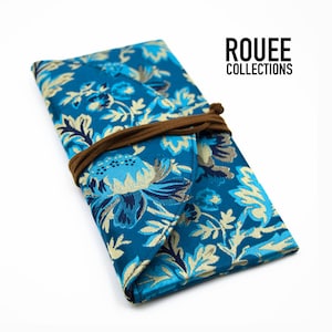 May include: A blue and gold floral patterned envelope clutch with a brown leather strap and the text "ROUEE COLLECTIONS".