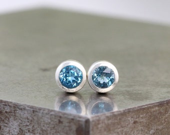 May include: A pair of silver stud earrings with round blue gemstones.