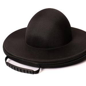 May include: A black hat case with a handle. The case is round with a dome-shaped top, and a zipper closure. The handle is black and has a ridged design. The case is designed to protect a hat.