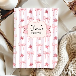 Puede incluir: Un diario con un fondo a rayas rosas y blancas, adornado con lazos rosas y motivos florales. La portada presenta el texto "Olivia's Journal" en una elegante escritura dentro de un marco decorativo. El diario está abierto, revelando páginas en blanco.