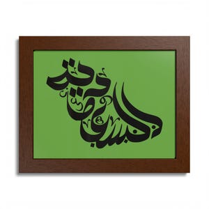 May include: A framed art print featuring black Arabic calligraphy on a green background. The artwork is enclosed in a dark brown wooden frame. The calligraphy is stylized and decorative.