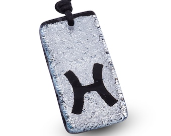 May include: A silver glass pendant necklace with a black Pisces zodiac symbol. The necklace has a black cord.