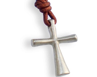 May include: A silver cross pendant on a brown leather cord necklace. The cross has a simple design with rounded edges.