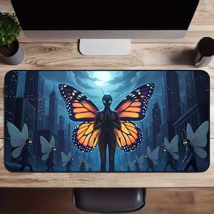 May include: Rectangular mousepad featuring a surreal illustration of a humanoid figure with butterfly wings in a city setting. The figure has orange and black wings and is surrounded by other similar figures. The background depicts a cityscape under a full moon.