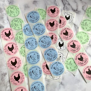 May include: A collection of round stickers with various designs. Some stickers feature a black silhouette of a chicken, while others display a chicken illustration. The stickers are in pink, blue, and green, with text such as "Farm Fresh Eggs" and "Laid with Love."