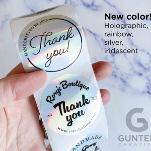 May include: Holographic, rainbow, and iridescent stickers with the words "Thank you!" and "Rory's Boutique" printed on them. The stickers are round and have a shiny, reflective surface. The text "New color!" is also visible.