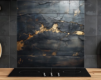 May include: A rectangular kitchen splashback panel featuring a dark, charcoal-coloured stone texture with prominent, jagged gold-coloured veins running horizontally across the centre, installed behind a black glass hob.